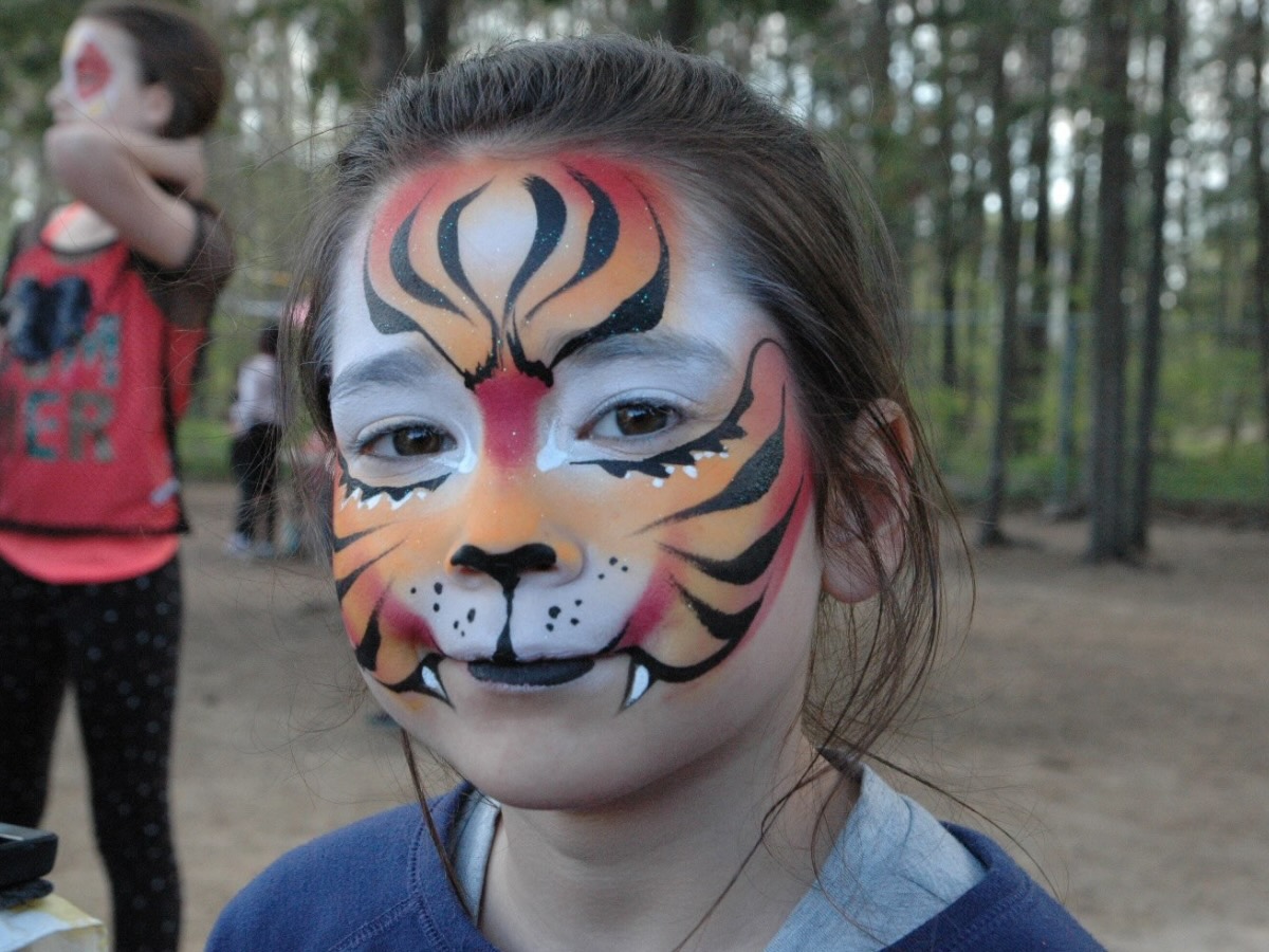 Fille maquillée en tigre, avec des motifs de rayures et un museau de félin peint sur le visage