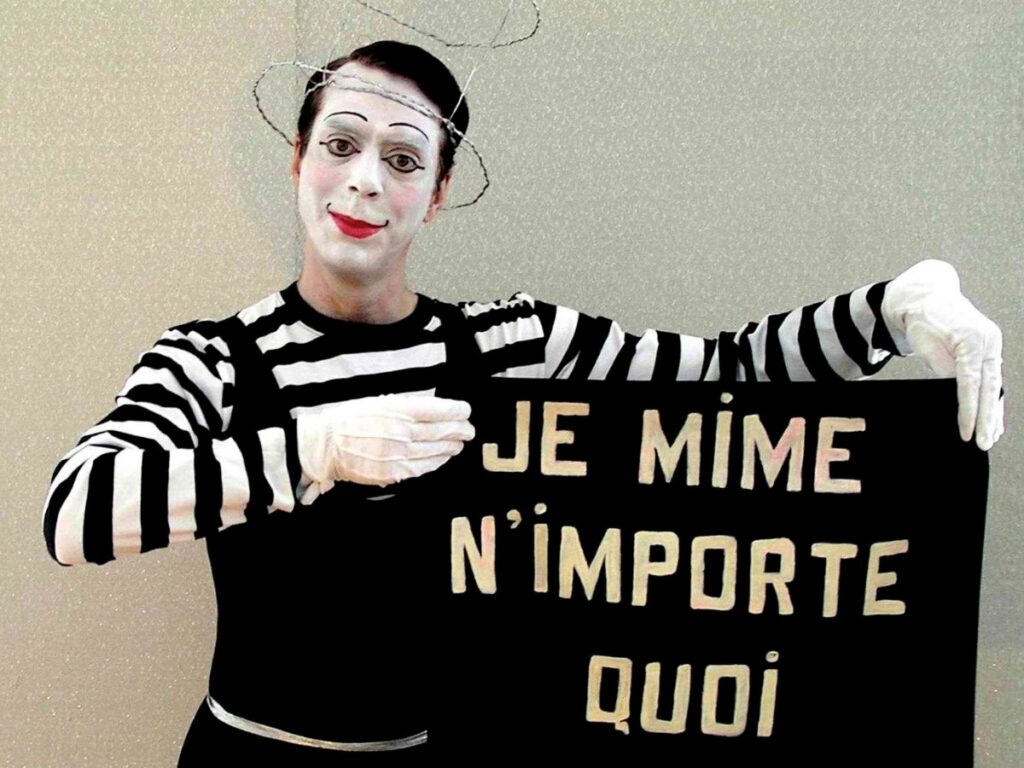 Homme déguisé en mime tenant une bannière avec des écriture