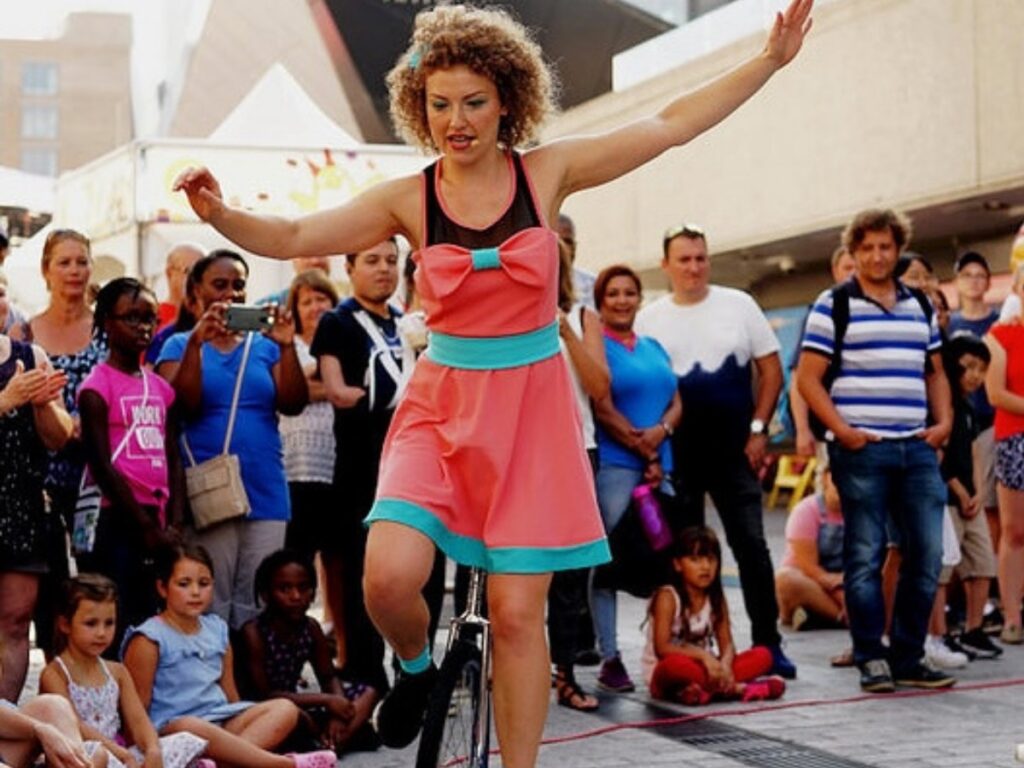 Femme déguisé sur un monocycle avec une foule derrière