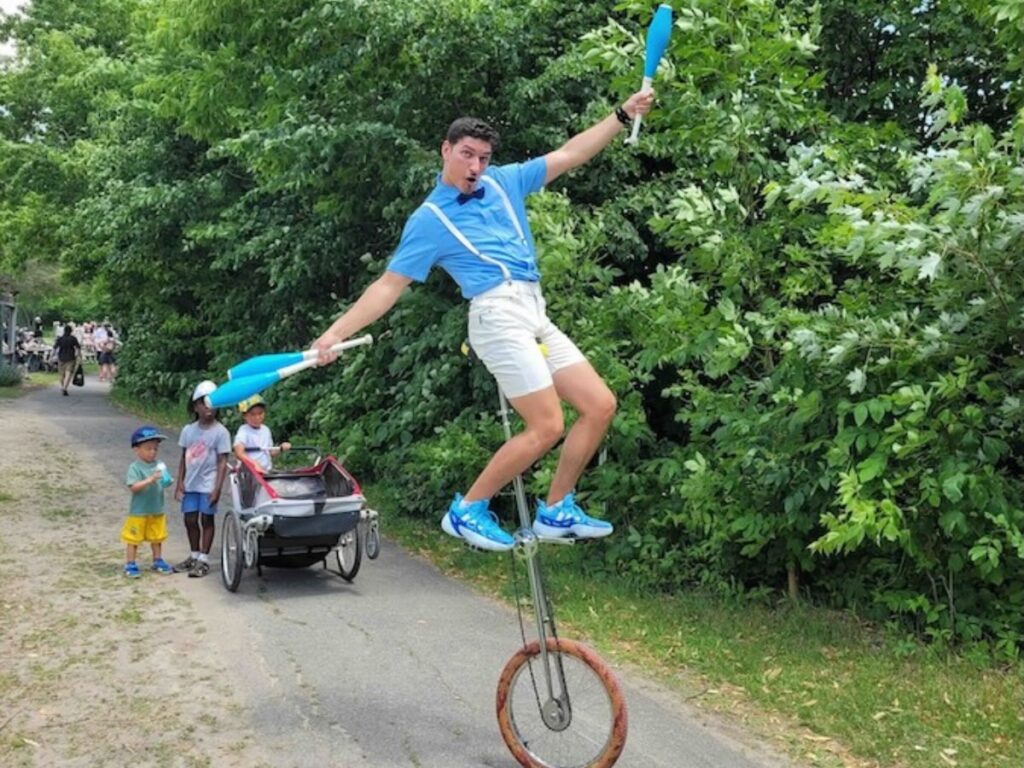 Homme sur un monocycle tenant trois quilles