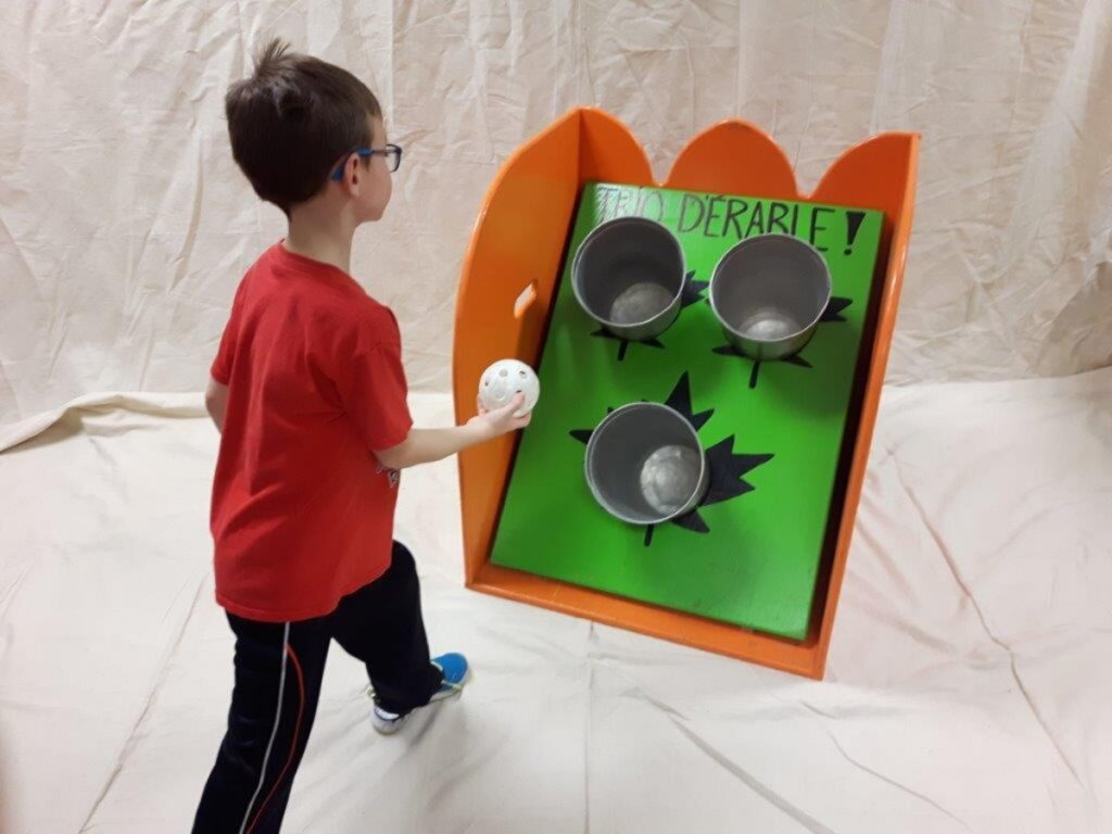 Enfant jouant avec des balles en les lançant dans des sceaux